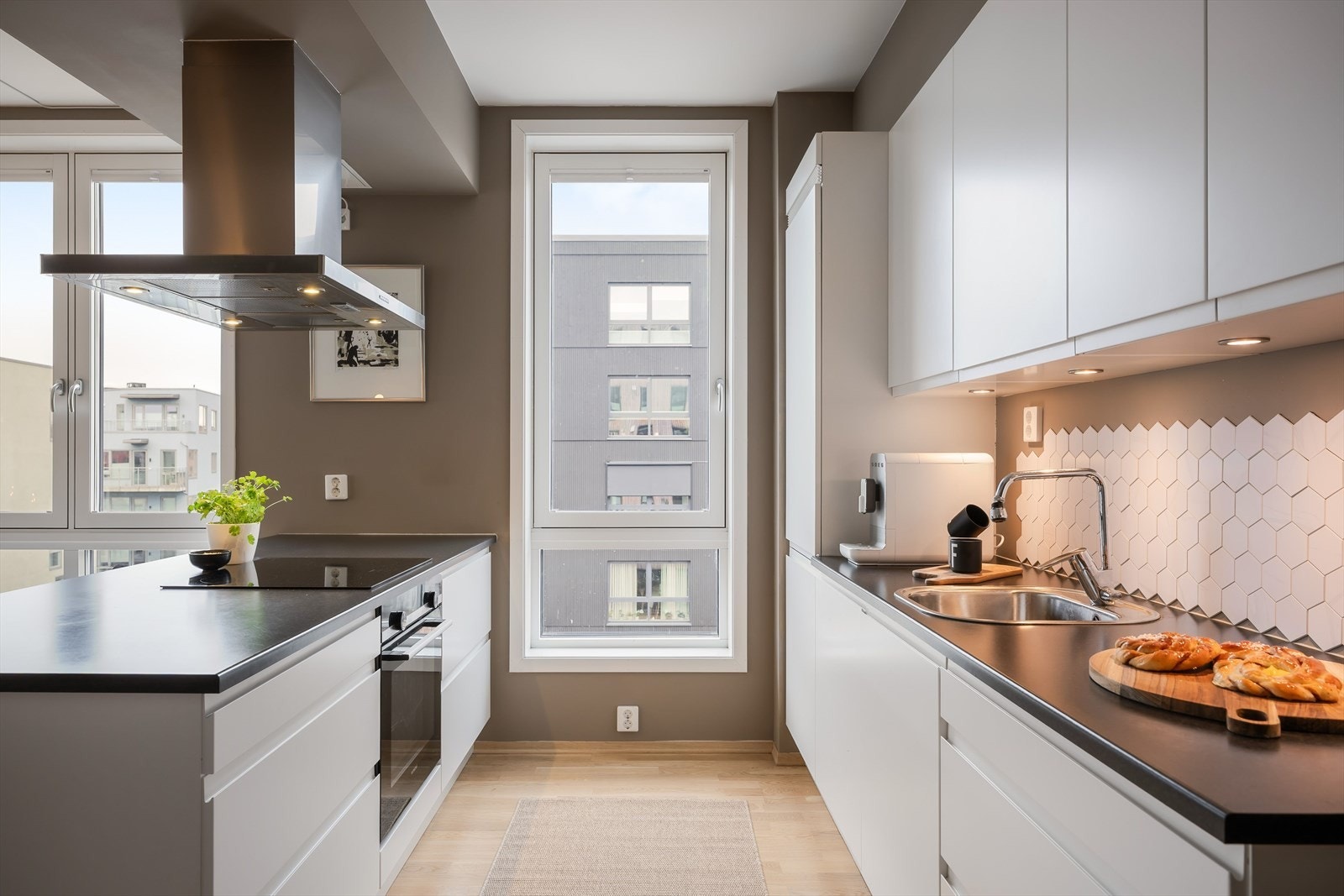 Det er et klassisk hvitt kjøkken med slette fronter og sort benkeplate. Galleribilde