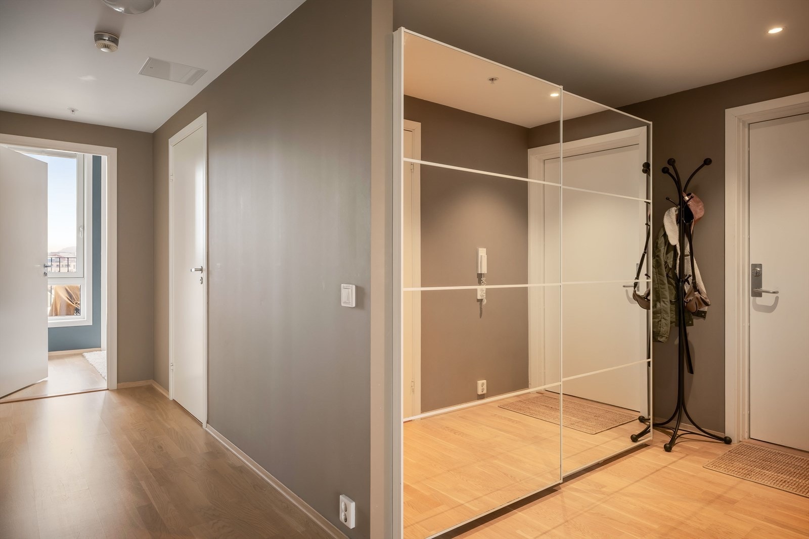 Boligen tar deg imot i en romslig entré med en stor skyvedørsgarderobe til oppbevaring. Galleribilde