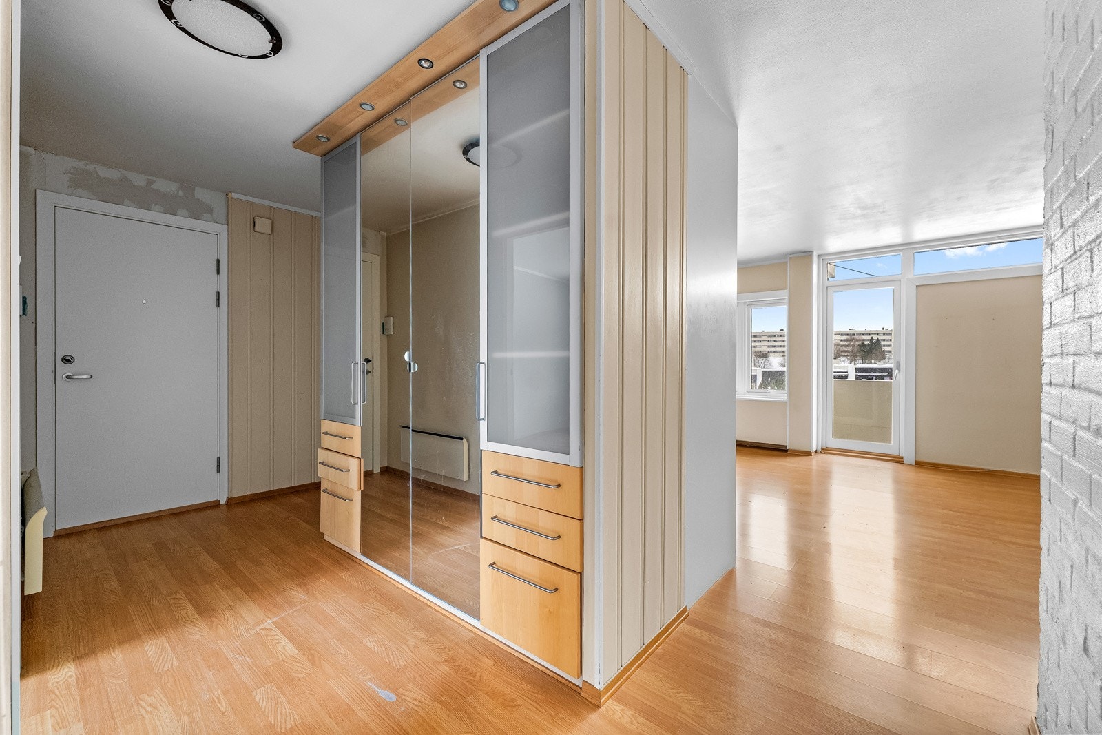 Entré med lysmalte veggflater og laminat på gulv. Det er montert et stort garderobeskap som gir gode oppbevaringsmuligheter. Galleribilde