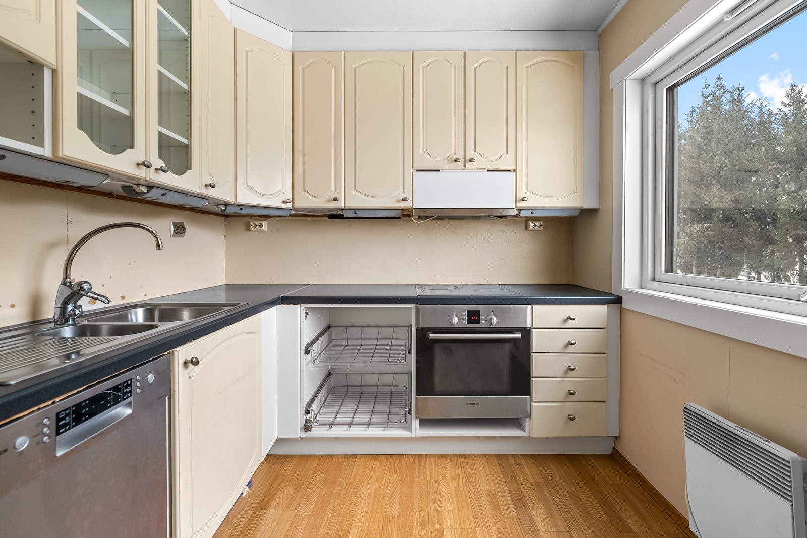 Separat kjøkken av eldre dato i praktisk vinkelløsning med god benke- og arbeidsplass. Innredningen har profilerte fronter, laminert benkeplate og nedfelt vaskekum. Galleribilde