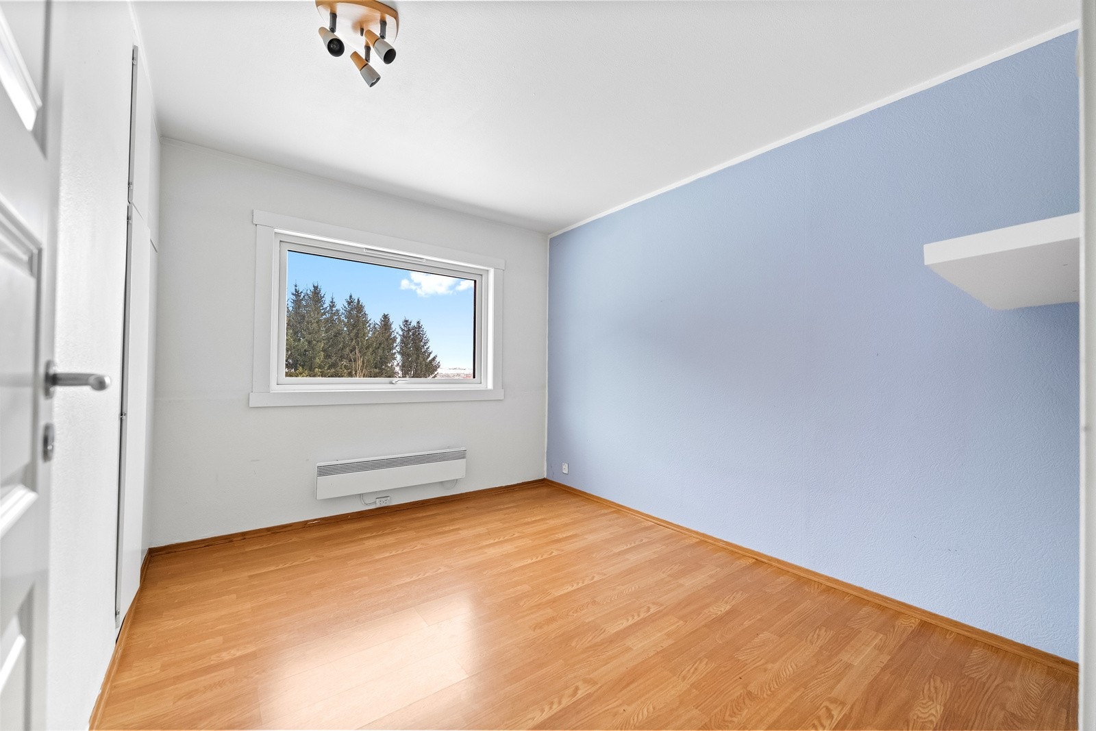 Leiligheten har ett romslig soverom med lysmalte veggflater og laminat på gulv. Stort vindu gir godt naturlig lysinnslipp. Galleribilde