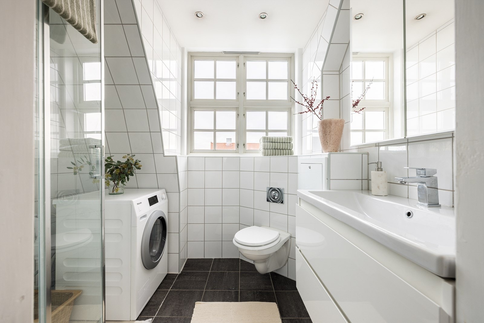 Lys og fint bad med vegghengt wc, servant med skuffer under, dusjkabinett og opplegg for vaskemaskin. Galleribilde