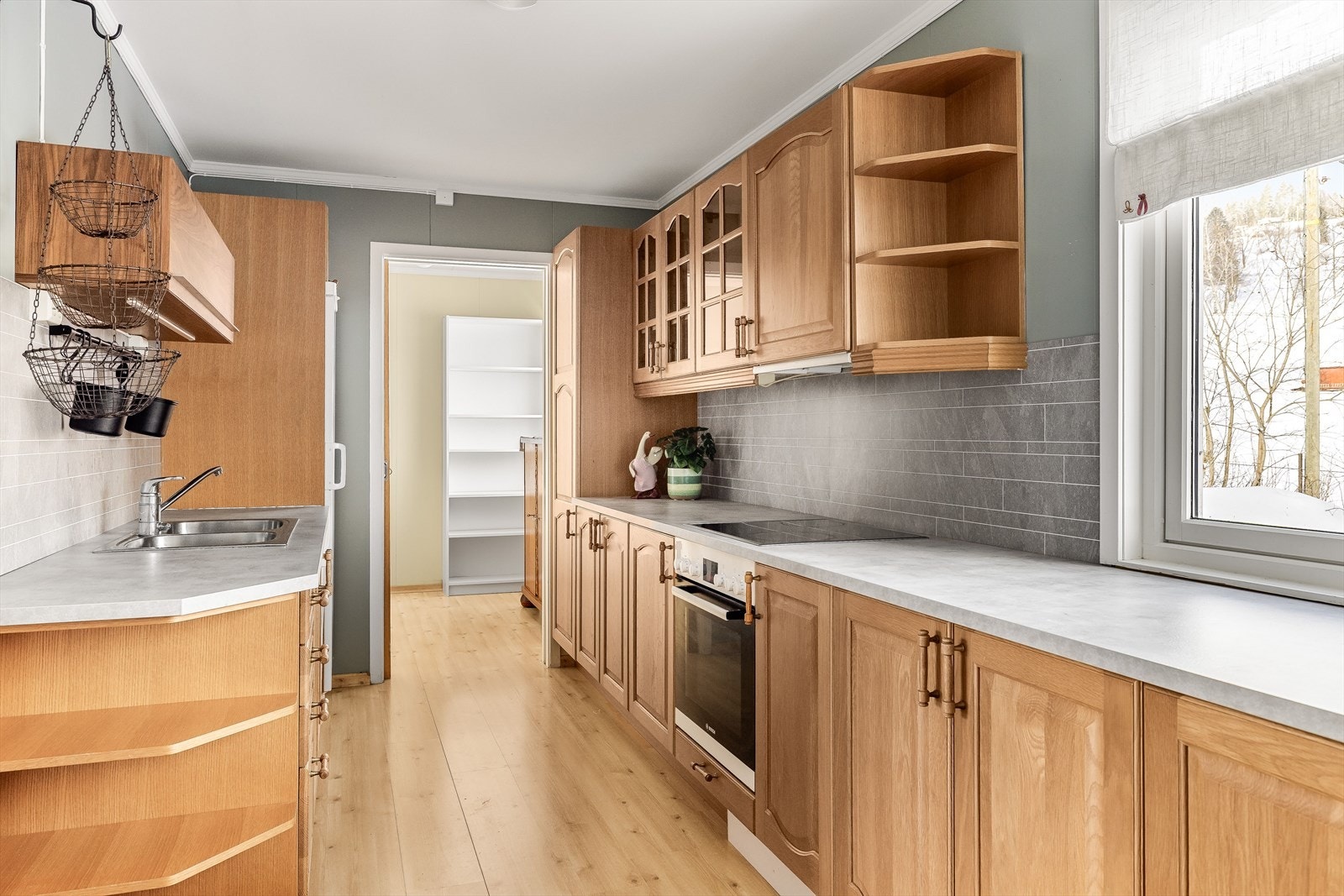 Innredningen har profilerte fronter og laminert benkeplate fra ca. 2020 med nedfelt oppvaskkum. Praktisk med fliser i benkeryggen og belysning under overskap. Galleribilde