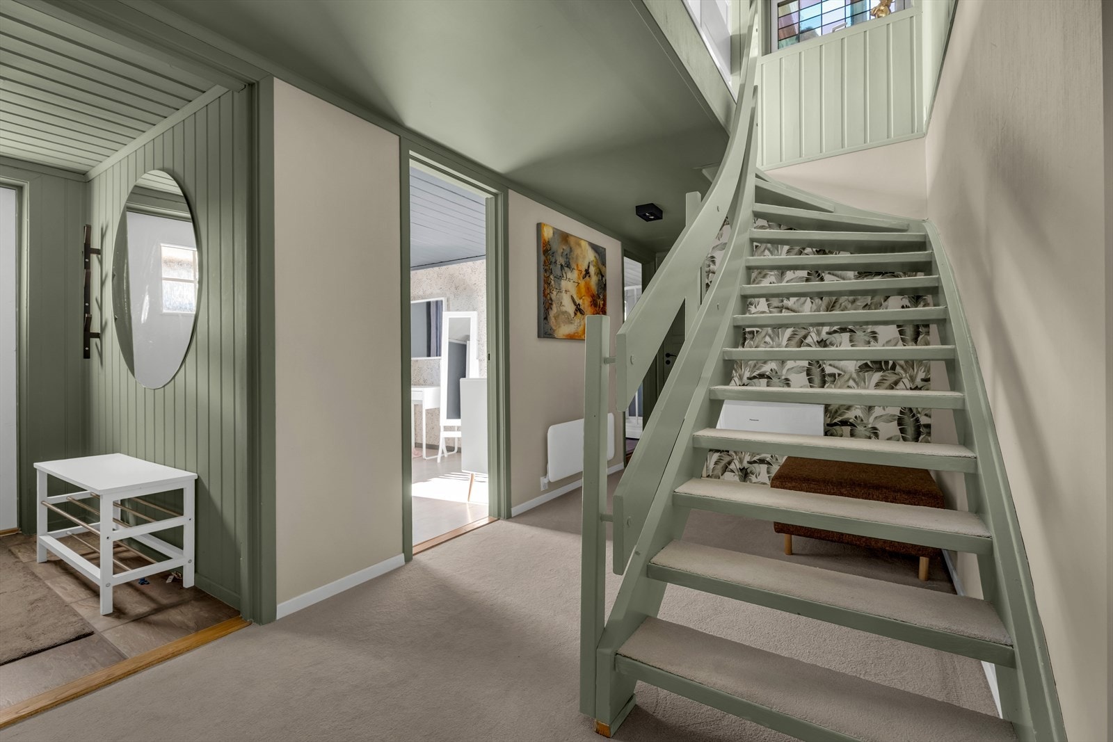 Den malte tretrappen med teppe i trinnene leder elegant opp til hovedetasje. Galleribilde