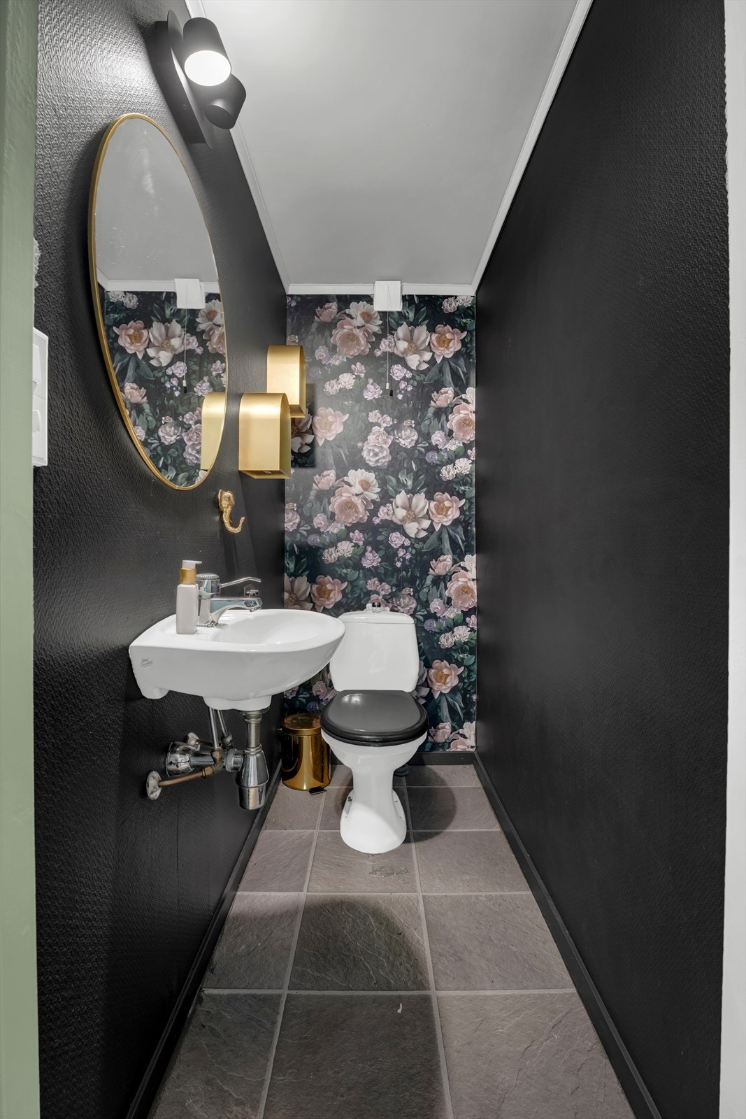 Praktisk toalettrom i underetasjen med tapet på veggene og laminat på gulv. Galleribilde