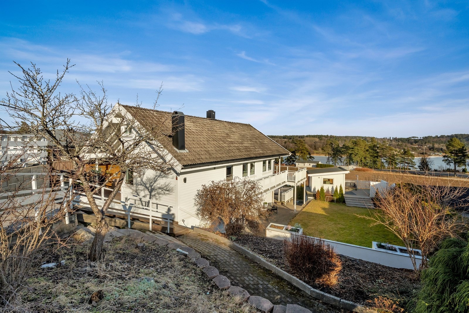 Tomten er skrånende og opparbeidet med plen og beplantning. Galleribilde