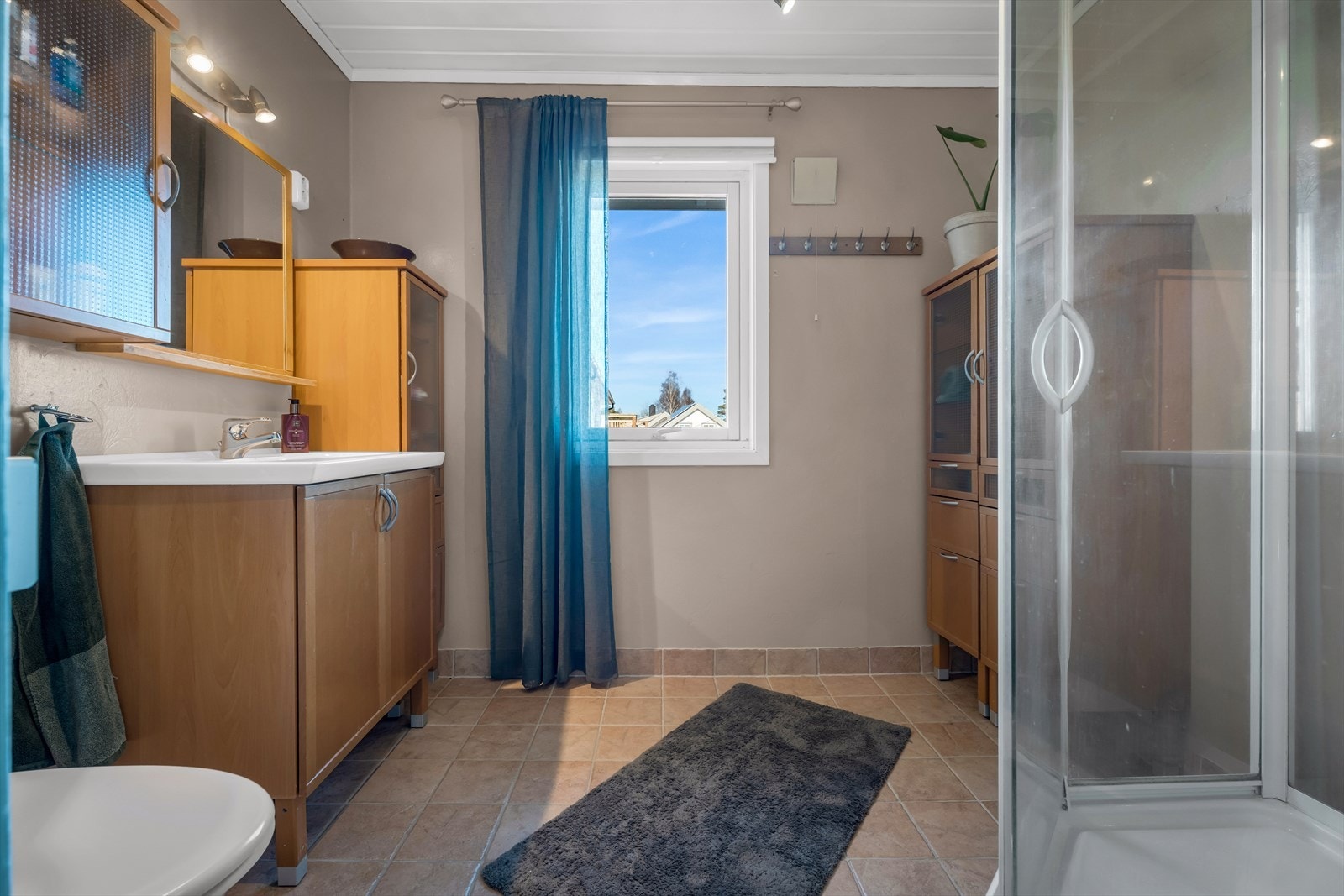 Badet i første etasje har flislagt gulv med varmekabler, dusjkabinett og servantinnredning. Galleribilde