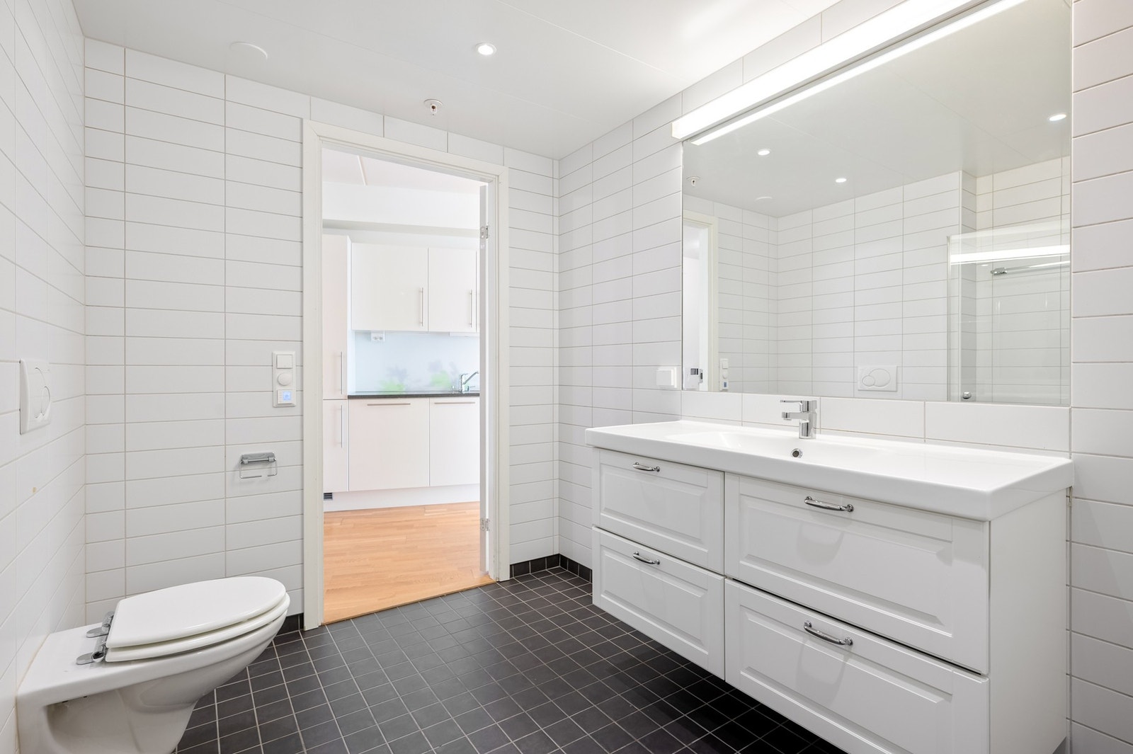 Pent bad med flislagte overflater, servant med god skapplass og speil med integrert belysning. Galleribilde