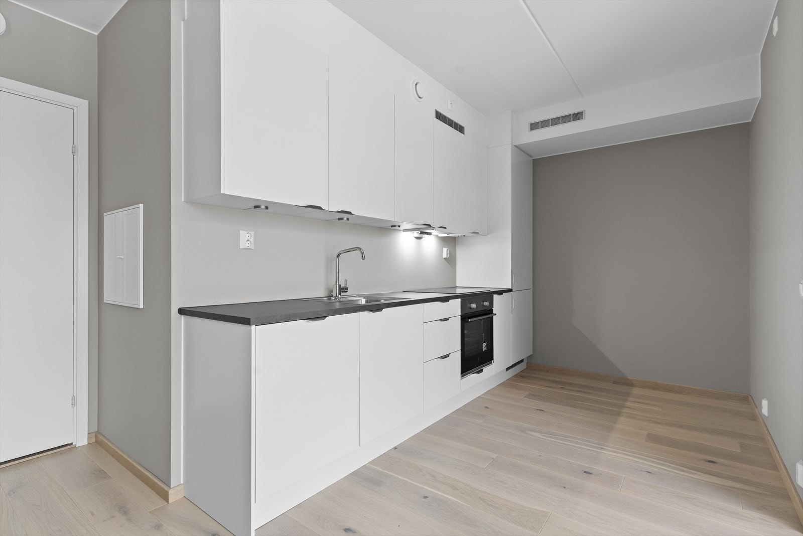 Kjøkken er fra Norema med fronter i Aspekt klassisk hvit og integrerte hvitevarer fra Elektrolux eller tilsvarende produkt fra annen leverandør. Utenpåliggende spotter under overskap med bryter og stikk på vegg. Håndtak i børstet stål Galleribilde