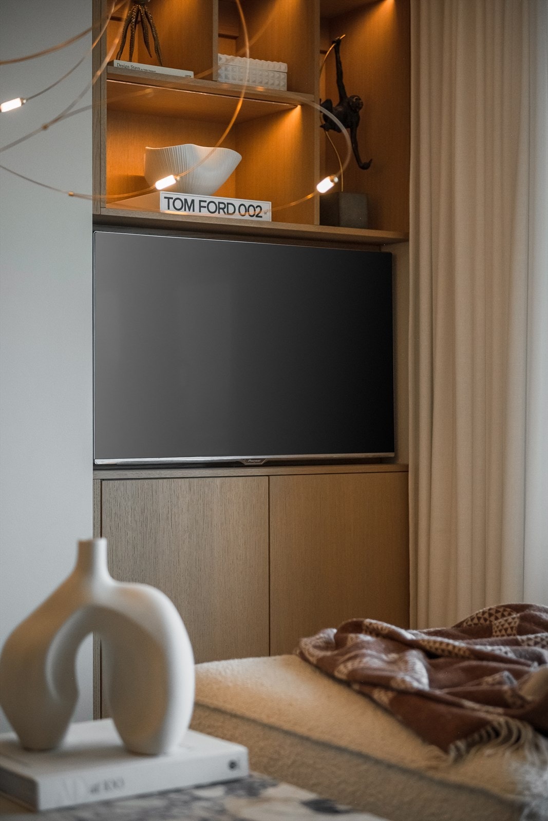 Snekkerbygget TV-seksjon i stuen med integrert oppbevaring og åpne hyller, hvor TV-en kan trekkes ut ved behov. Galleribilde