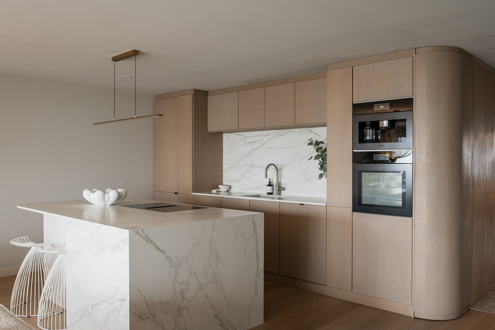 Stilren kjøkkenøy i steinkompositt (Dekton) med nedfelt platetopp og integrert ventilator. Kjøkkenet er plassbygget fra Snekkeriet med fronter i eik. Galleribilde