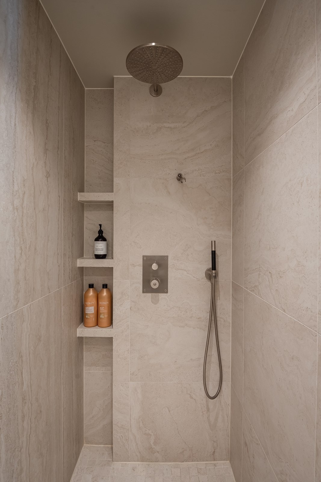 Dusjsone med praktisk nisje for oppbevaring og gjennomgående flislagt utførelse. Galleribilde