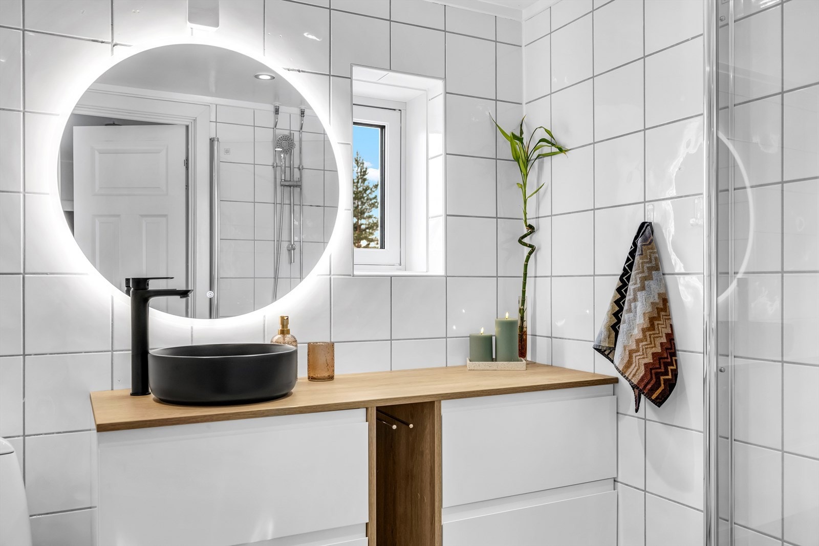 Rommet er innredet med klosett, servant plassert på baderomsinnredning, speil med belysning samt dusjhjørne med svingbare glassdører. Galleribilde