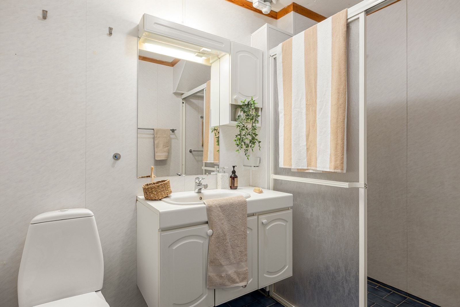 Bad med servantinnredning, speilskap og toalett. Praktisk løsning med oppbevaringsplass og tilknyttet dusj. Galleribilde