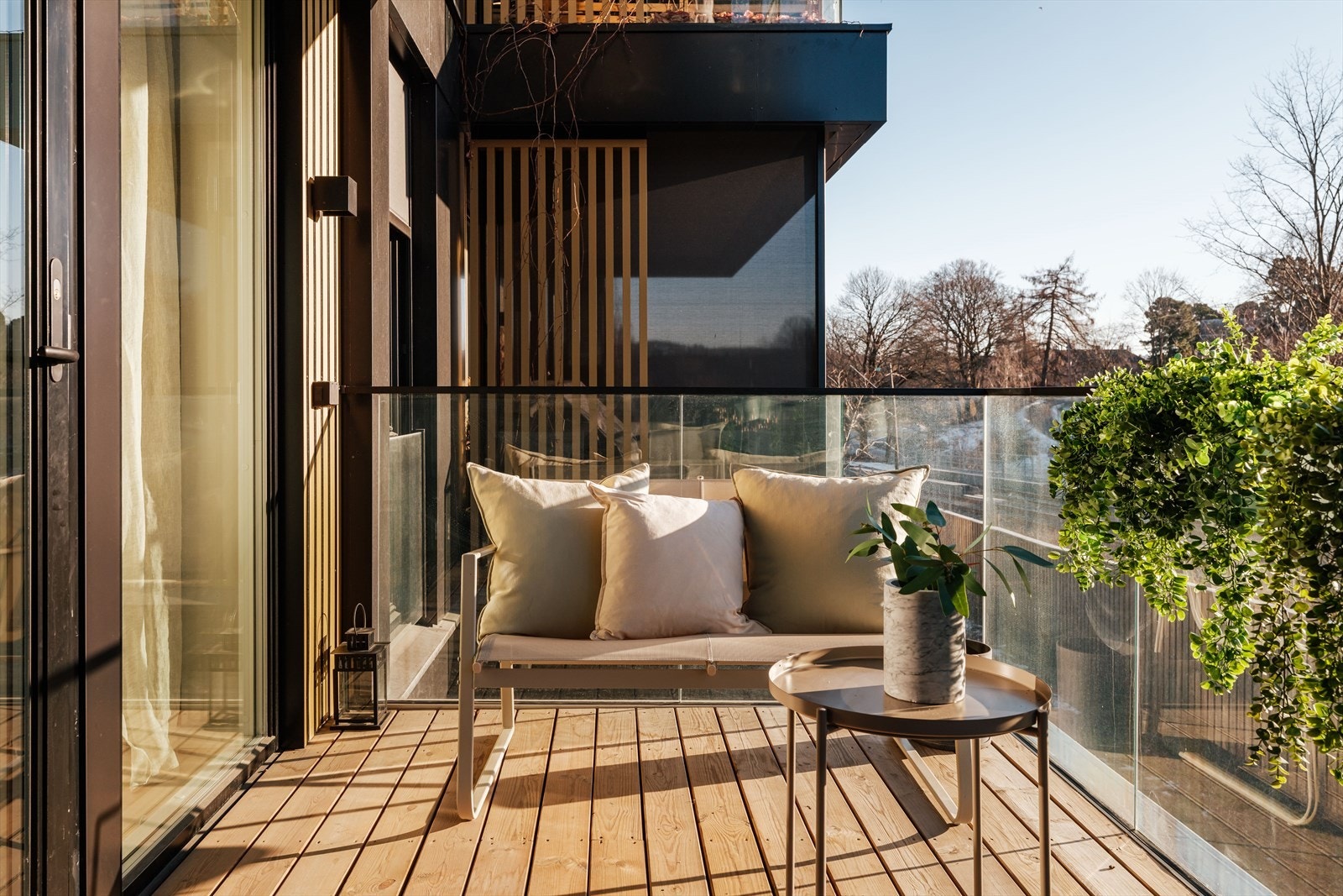 Balkongen er utført med betongdekke og et moderne rekkverk i glass. Takoverbygget gir god skjerming mot vær og vind, og bidrar til at uteplassen kan brukes store deler av året. Galleribilde