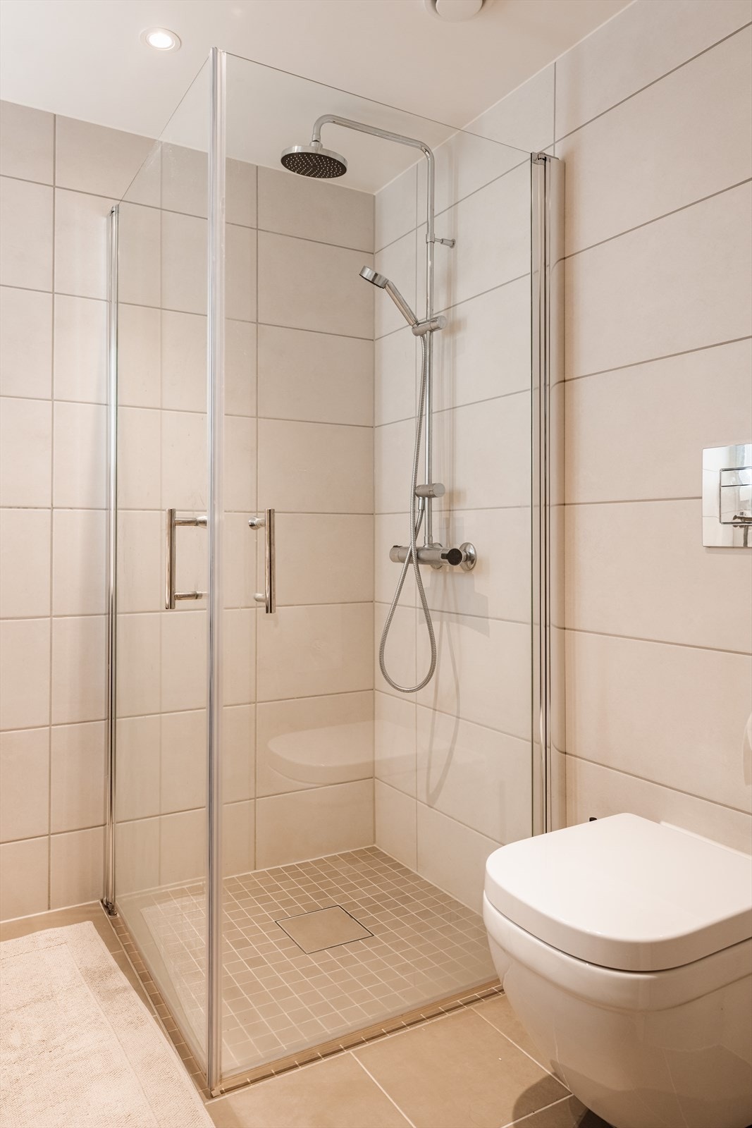 Badet er også utstyrt med vegghengt toalett og dusjhjørne med svingbare glassdører. Galleribilde