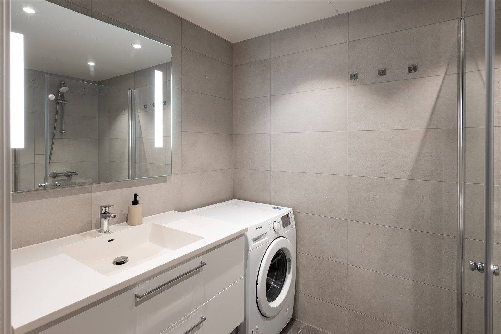 Stilrent og flislagt baderom på 4m². Det er rikelig med oppbevaringsplass i baderomsinnredningen. Galleribilde