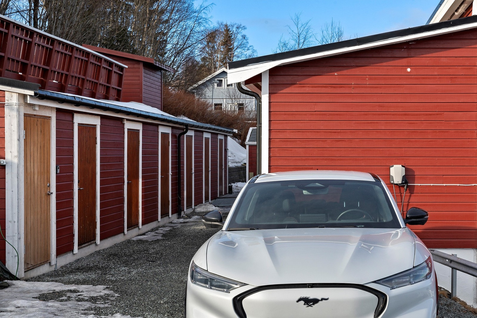 Med leiligheten følger fast parkering på oppstillingsplass. Her er det allerede montert opp elbil-lader som medfølger i handelen. Privat sportsbod på 5 kvm. til venstre i bildet. I tillegg kommer nok en bod utenfor inngangsdør på 2,5 kvm. Galleribilde