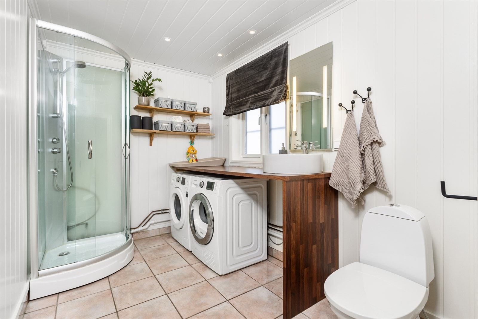 Badet et utstyrt med toalett, dusjkabinett og opplegg til vaskemaskin. Det er elektrisk styrt vifte i tak. Galleribilde