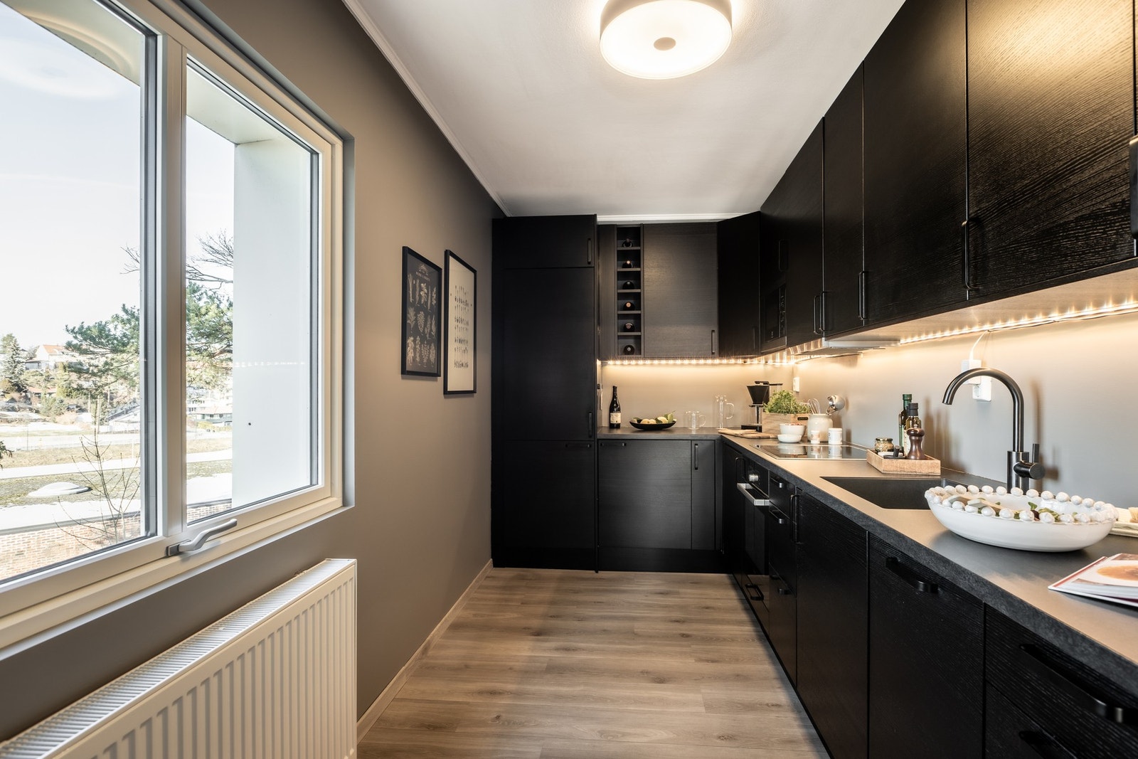 Moderne kjøkken med integrerte hvitevarer og stilrene, mørke fronter. Galleribilde