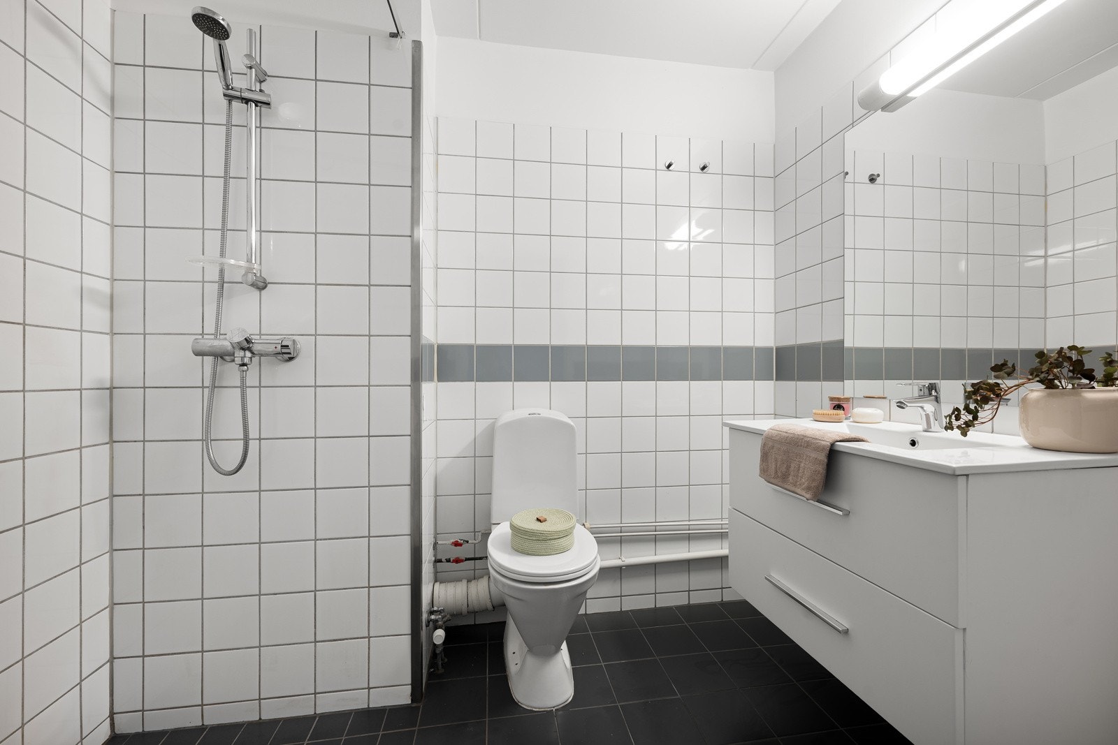 Badet er innredet med servant med underskuffer, speil med belysning og toalett. Galleribilde