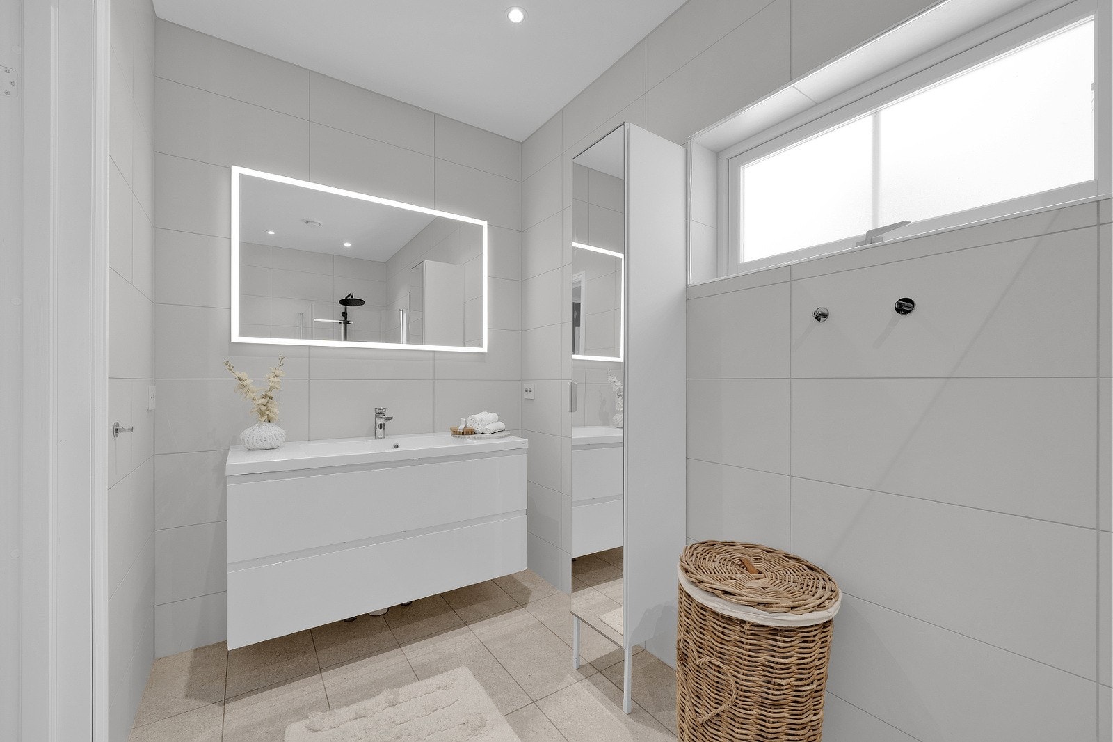 Badet er utstyrt med servant med ettgrepskran og skuffer under, speil med innebygd lys langs kanten, vegghengt toalett med skjult sisterne, samt høyskap på vegg for praktisk oppbevaring. Galleribilde