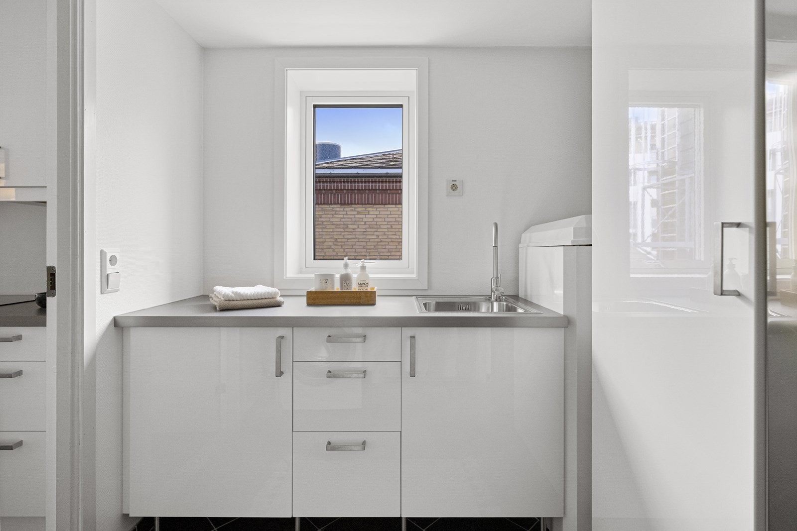 Vaskerom/bod innredet med vaskeromsløsning. Rommet har kjøkkeninnredning med servant og opplegg for vaskemaskin og tørketrommel. Galleribilde