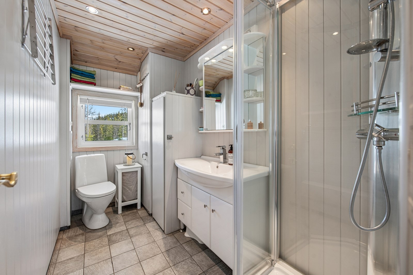 Badet har flislagt gulv med elektriske varmekabler og et praktisk dusjkabinett. Galleribilde