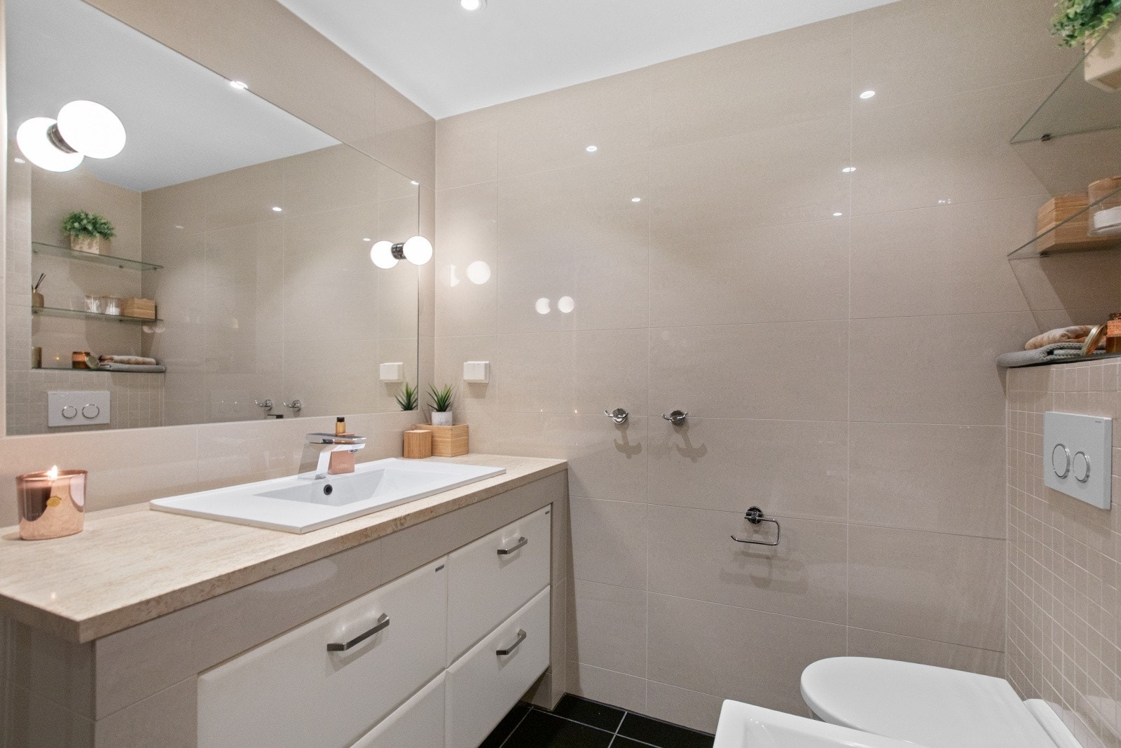 Badet er utstyrt med badekar og dusjvegg, servant med underskap, vegghengt toalett og et stort speil med belysning. Galleribilde