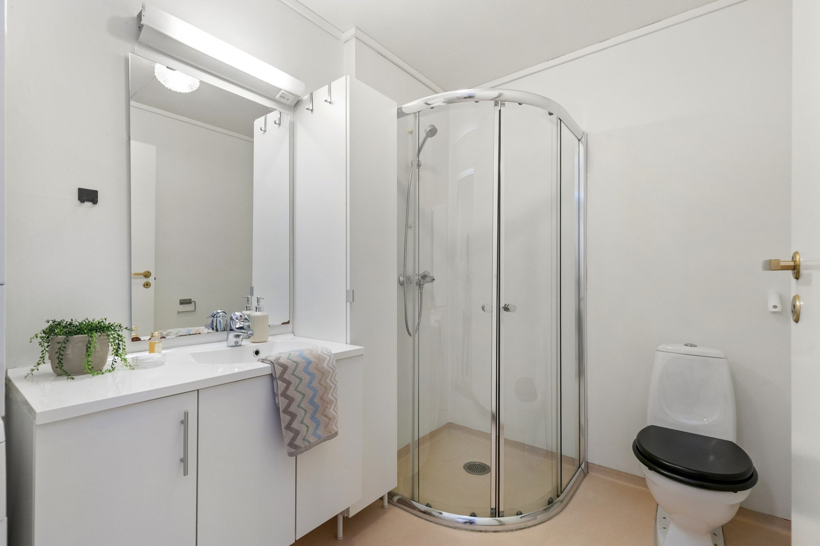 Lyst og funksjonelt bad med dusjkabinett, toalett og god oppbevaringsplass i romslig servantinnredning. Et praktisk og velholdt rom med alt du trenger i hverdagen. Galleribilde