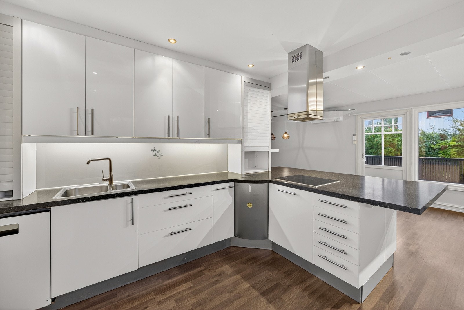 Kjøkkeninnredningen består av lyse slette fronter med belysning under overskap og laminat benkeplate med nedfelt kum i rustfritt stål. Av integrerte hvitevarer medflølger stekeovn, platetopp, kjøl/frys og oppvaskmaskin. Galleribilde