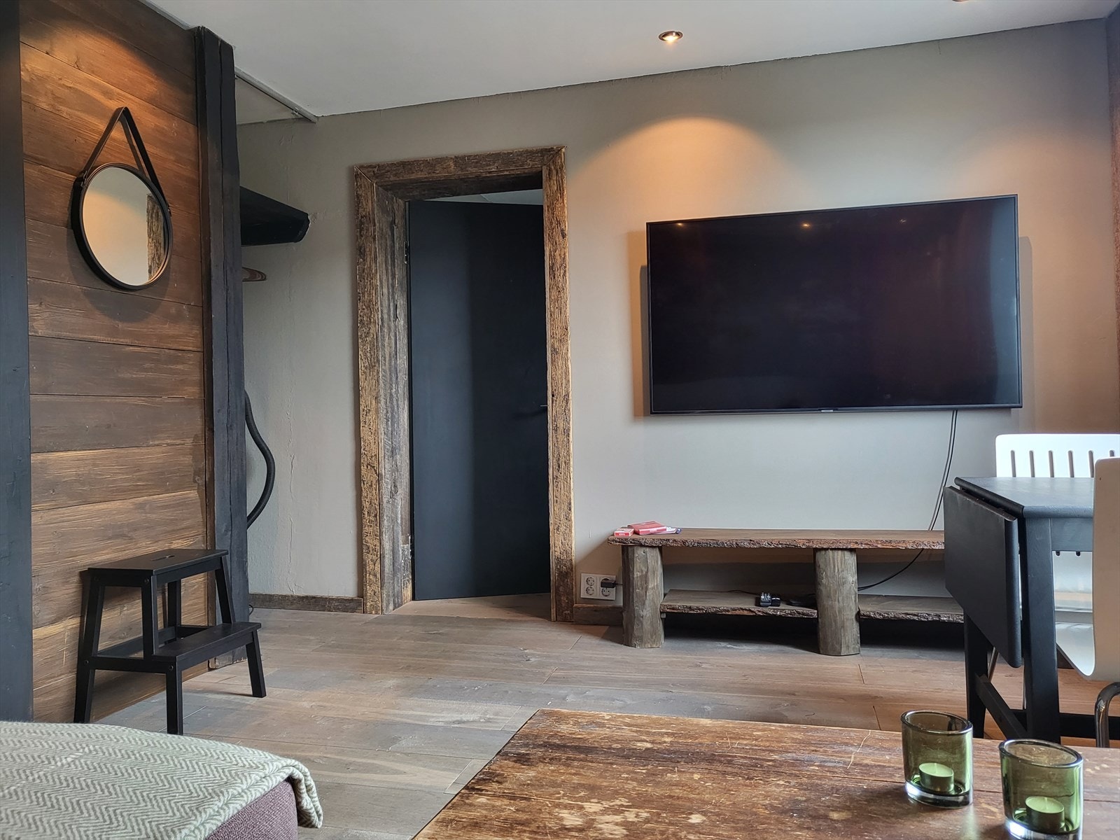 Vegghengt TV og TV-benk har fått sitt eget lille hjørne i stua, noe som gir rommet et ryddig og velbalansert preg. Galleribilde