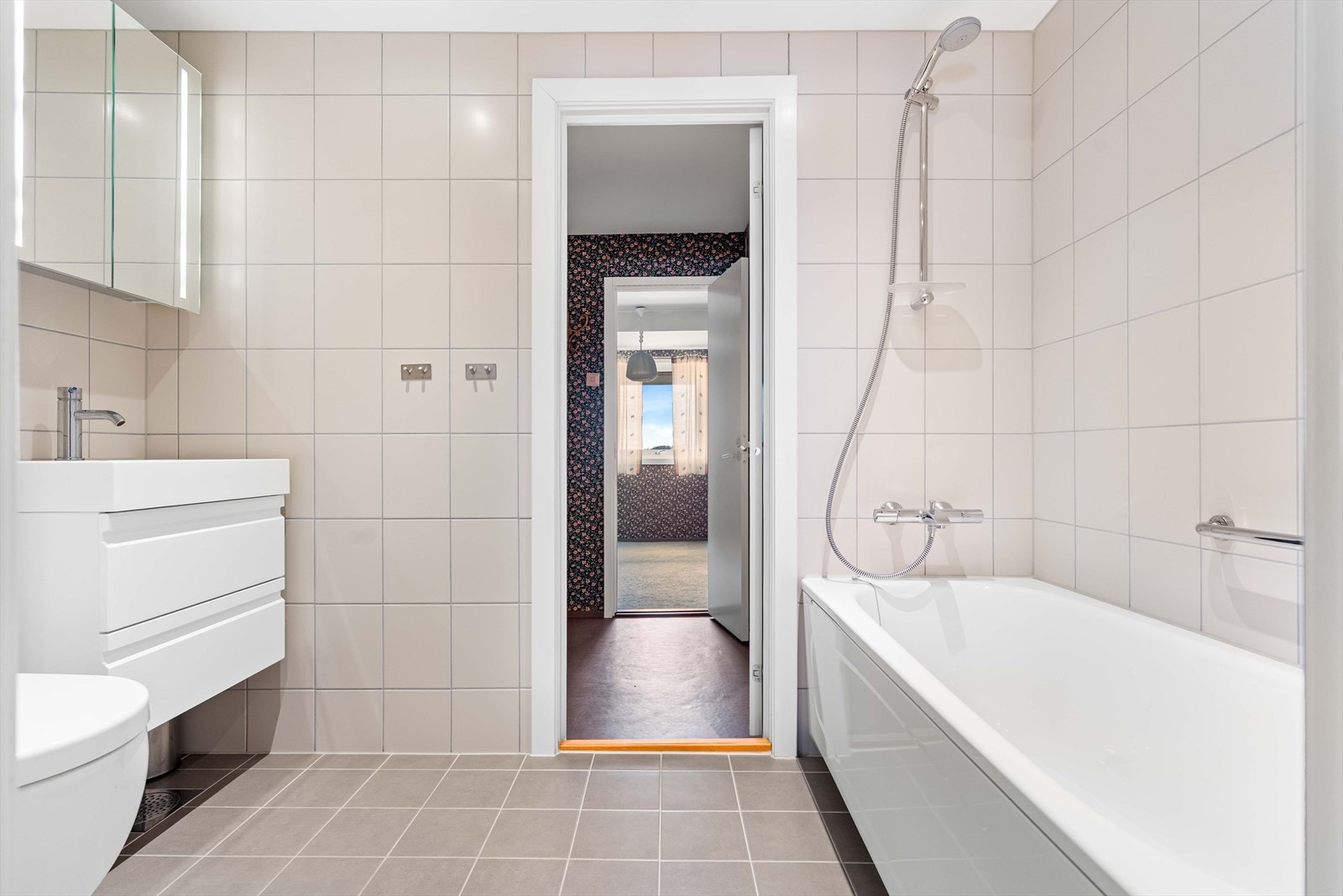 Badekar med dusjmulighet og flislagte vegger gir fleksibilitet i hverdagen. Galleribilde