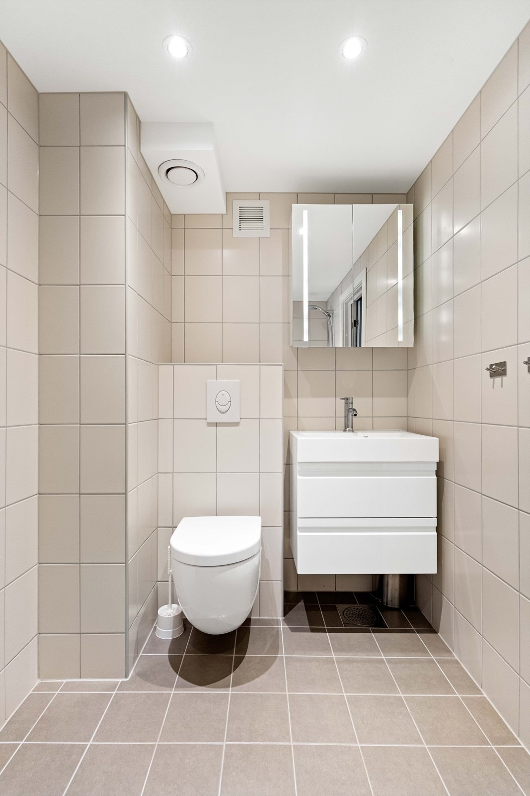 Nyere og flislagte vegger og gulv gir et robust og lettstelt bad med vegghengt toalett. Galleribilde