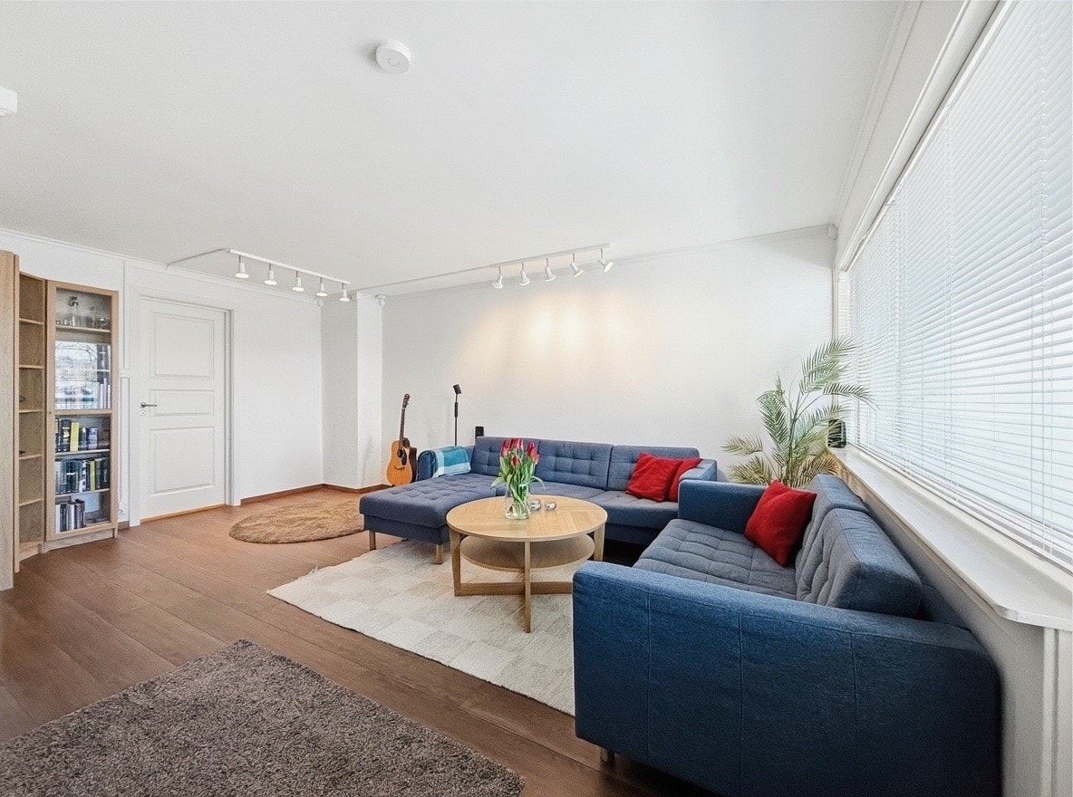 Lys stue med hjørnesofa og store vinduer som slipper inn mye dagslys Galleribilde