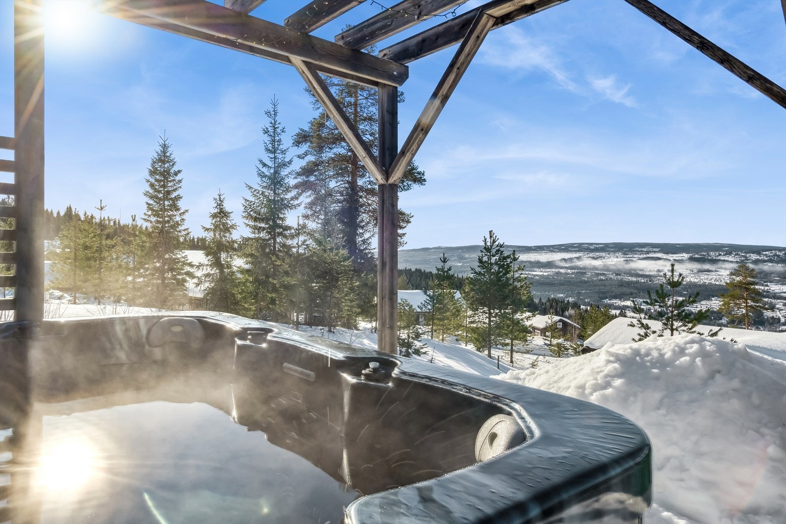 Ute på terrasseplattingen er det et utendørs boblebad, under en pergola. Galleribilde