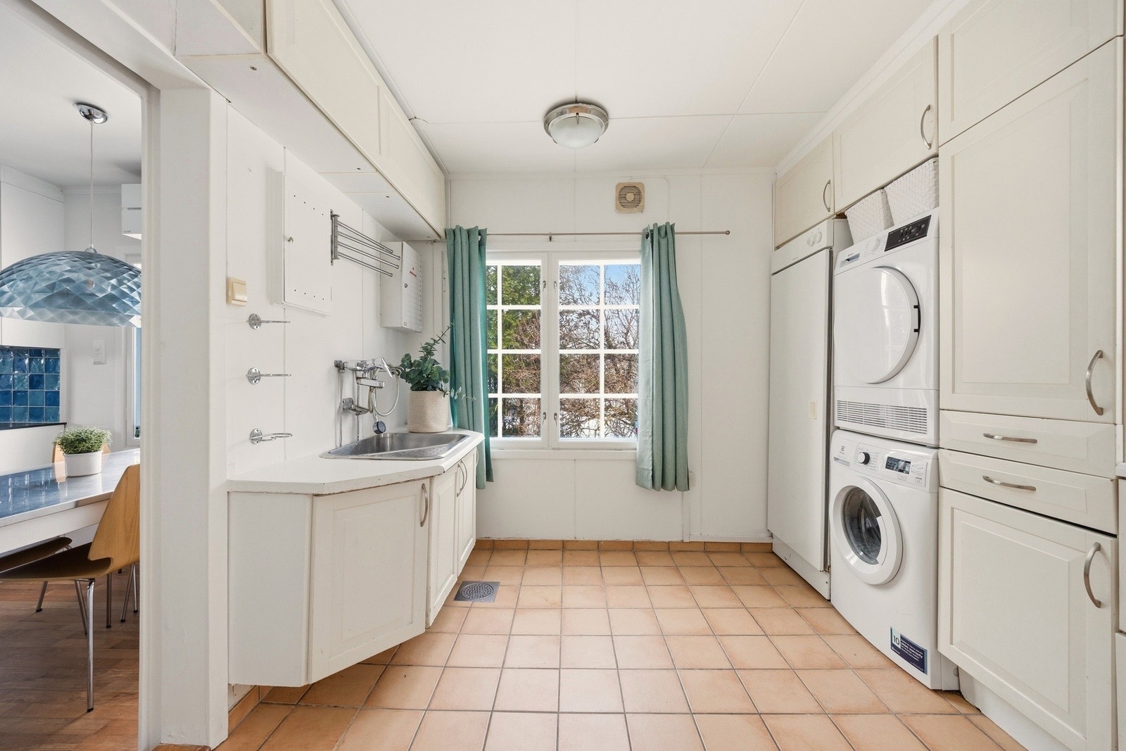 Mellom kjøkkenet og kjøkkeninngangen finner du et praktisk vaskerom med vaskesøyle og tørkeskap. Galleribilde