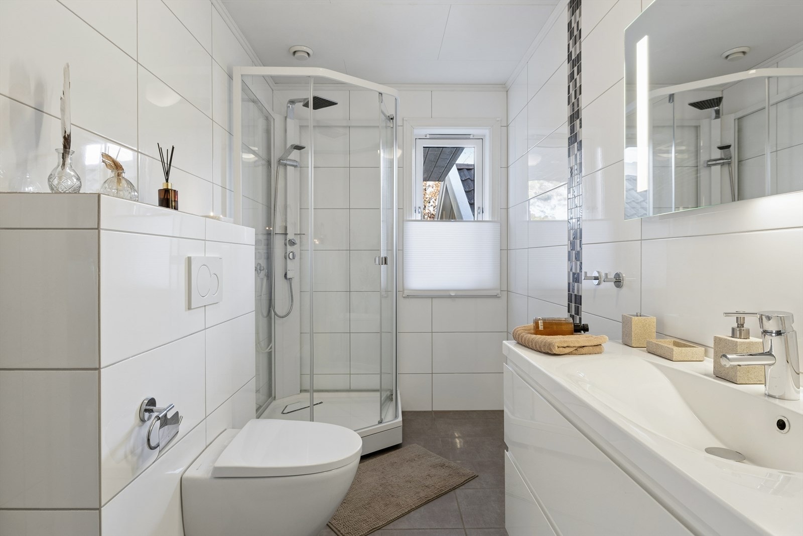 Innredningen består av vegghengt toalett, dusjkabinett og en heldekkende servant med god skapplass. Galleribilde