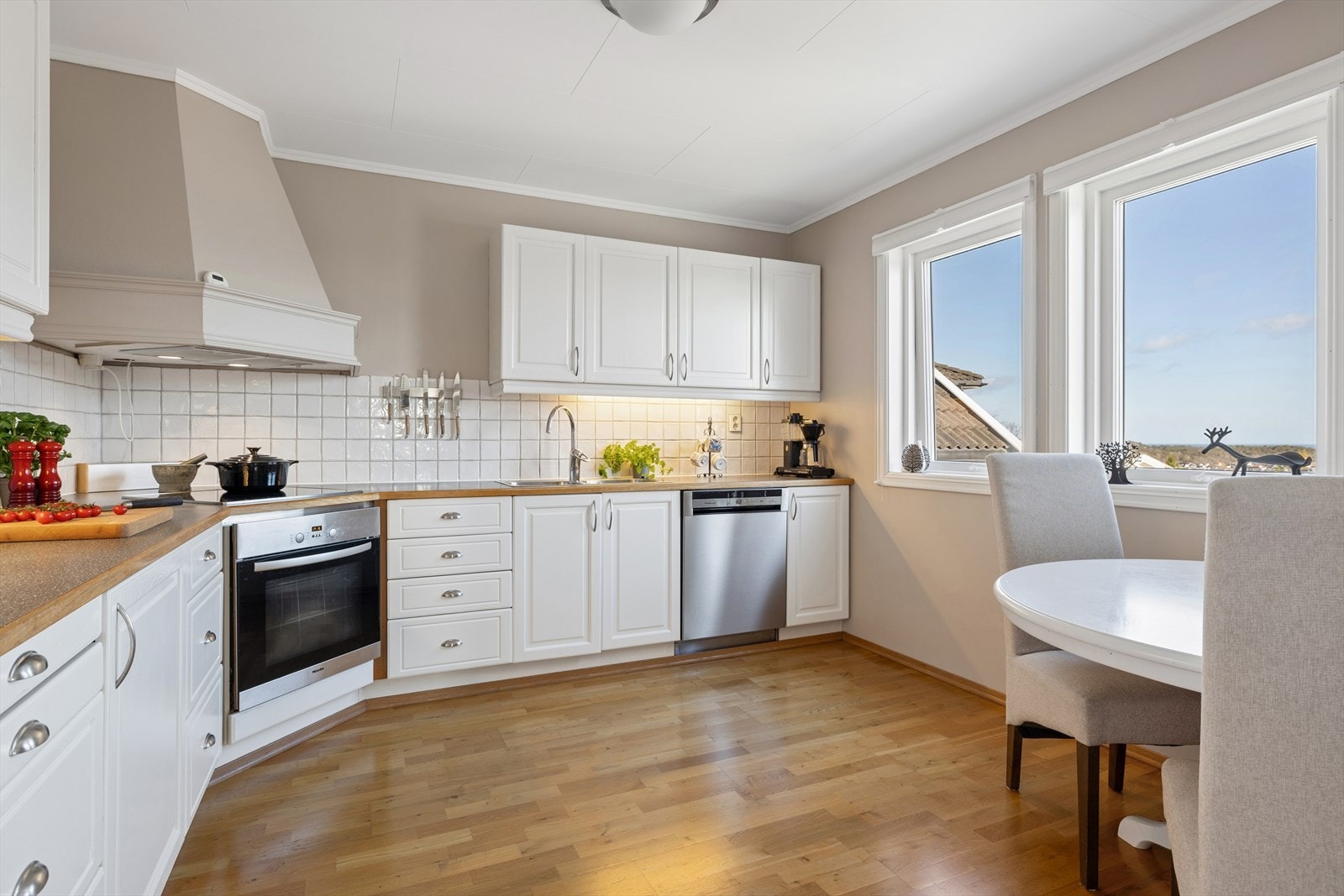 Kjøkkenet har en praktisk innredning med speilfronter og fliser mellom over- og underskap. Galleribilde