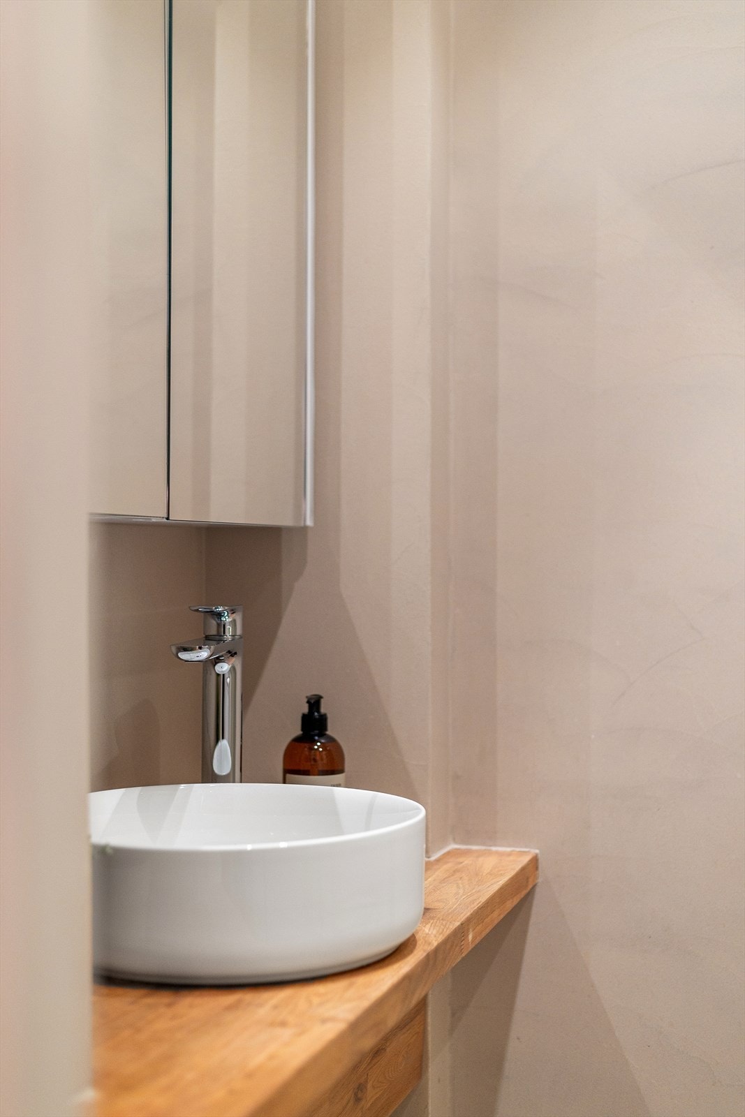 Badet er innredet med en servant på benkeplate, overhengende speilskap, belysning og opplegg til vaskemaskin. Galleribilde