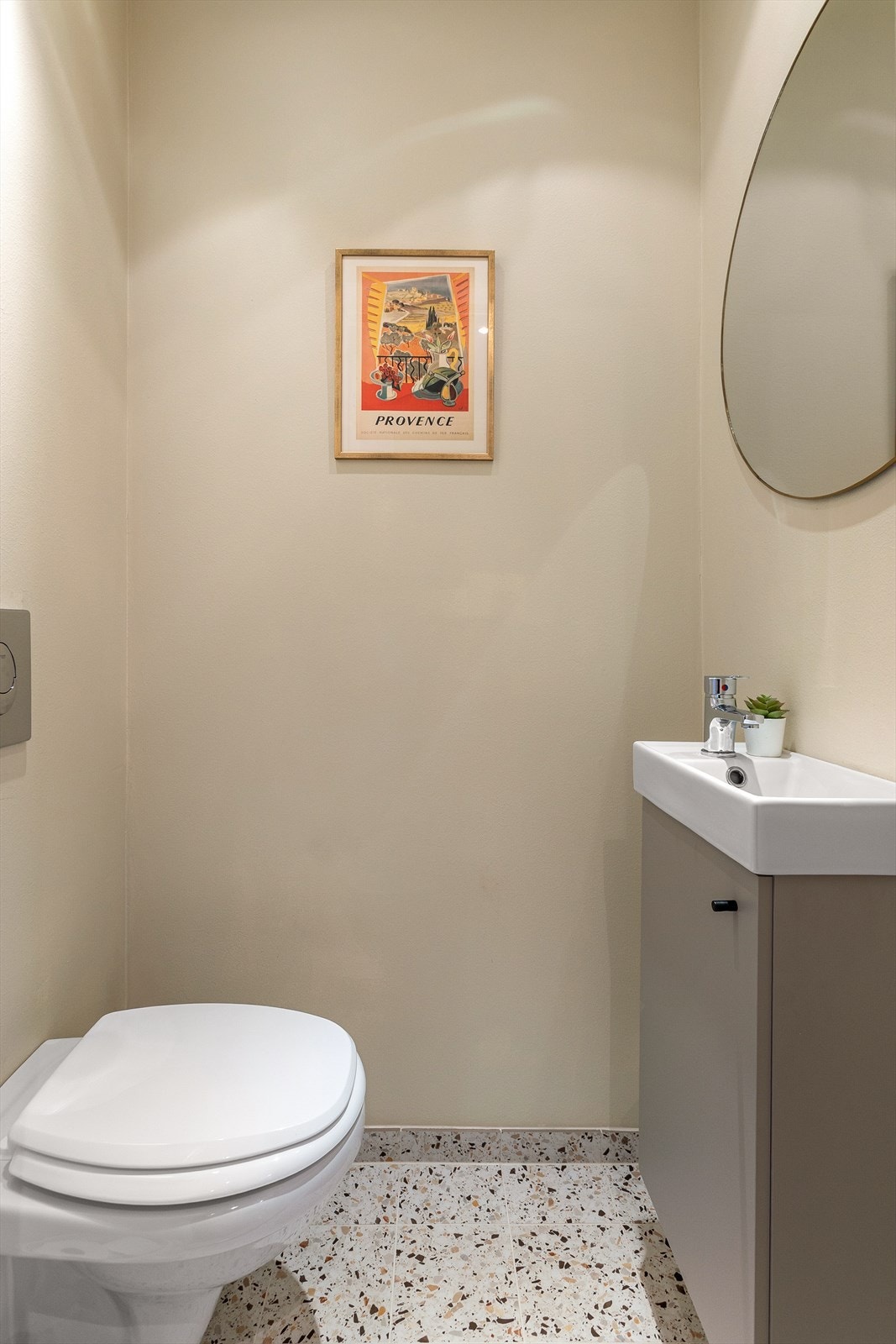 Toalettrom med flislagt gulv og malte vegger. Rommet er innredet med nedfelt servant og et vegghengt toalett. Galleribilde