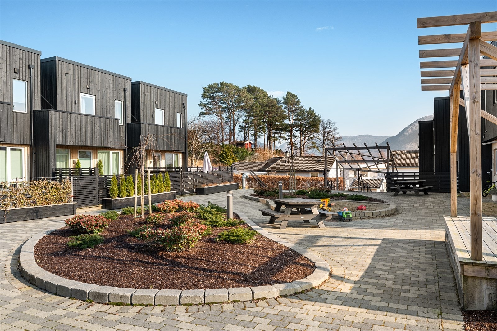 Utbygger har virkelig prioritert uteområdene med belegningsstein, plantefelt, sandkasse, lekeplass og flere sitteplasser. Galleribilde