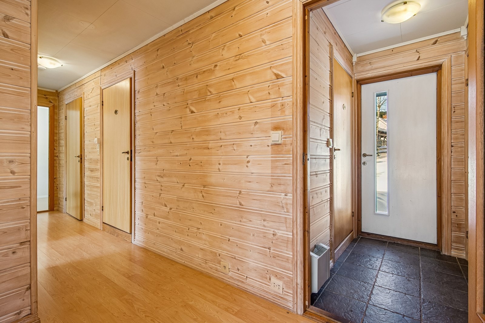 Fra entreen med flislagt gulv kommer du videre inn i boligens gangareal. Galleribilde