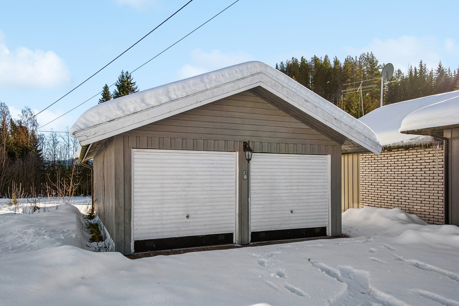 Den frittliggende garasjen fra 1996 har innlagt strøm og to vippeporter av tre. Galleribilde