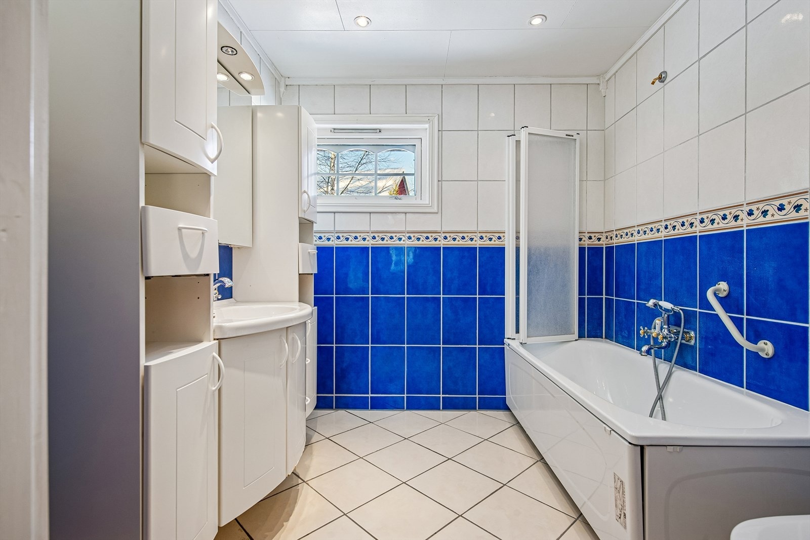 Badet er flislagt og utstyrt med badekar, servant med underskap og varme i gulvet. Galleribilde