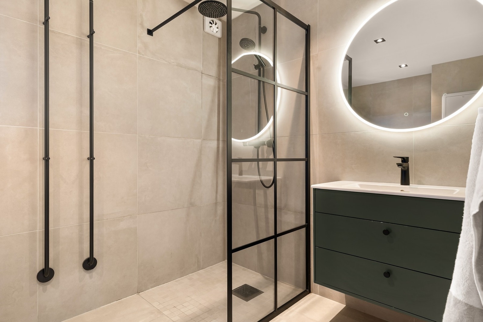 Delikat bad innredet med nedfelt servant, veggmontert toalett, dusjhjørne og opplegg for vaskemaskin. Galleribilde