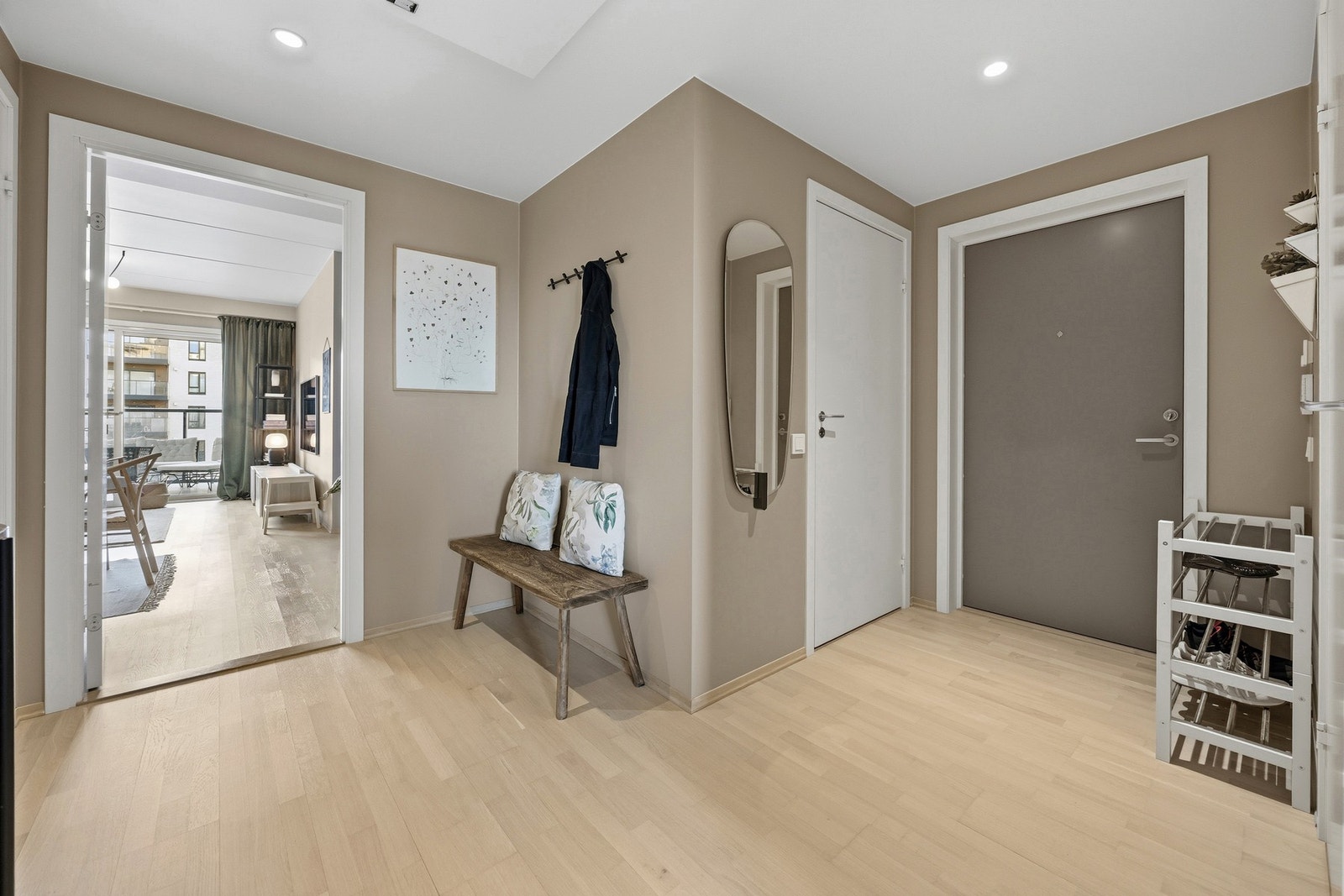 Tiltalende entré med hvitpigmentert trestavs parkett på gulv og lysmalte veggflater som gir et godt førsteinntrykk av leiligheten. Det er montert dørcalling ved inngangsdøren. Galleribilde