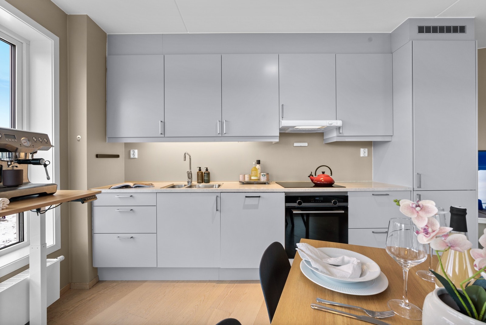 Moderne kjøkken med integrerte hvitevarer, ventilator over kokesonen og nedfelt vaskekum med ettgreps blandebatteri. Galleribilde