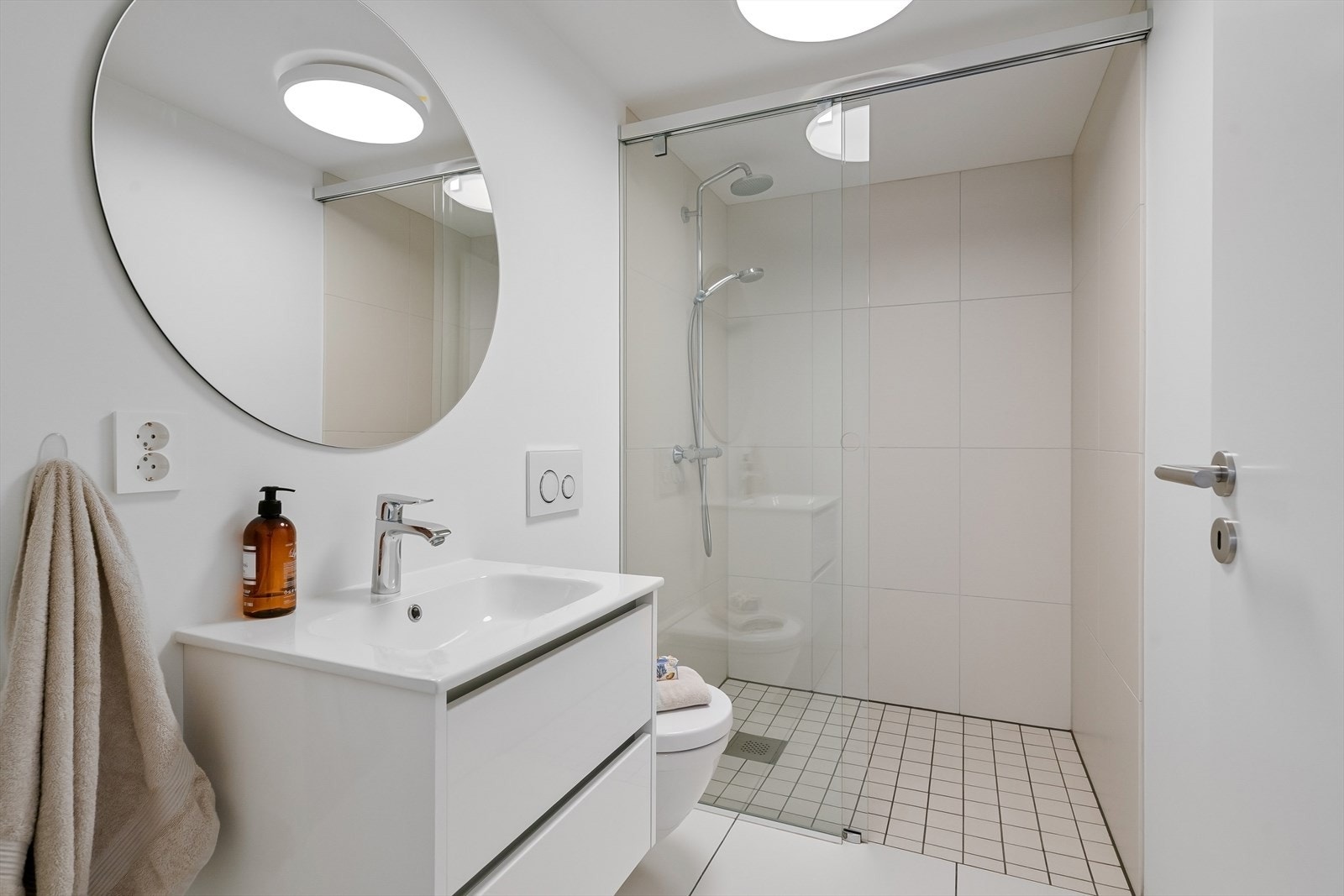 Pent flislagt bad med dusj, vegghengt toalett og servant med innredning. Galleribilde