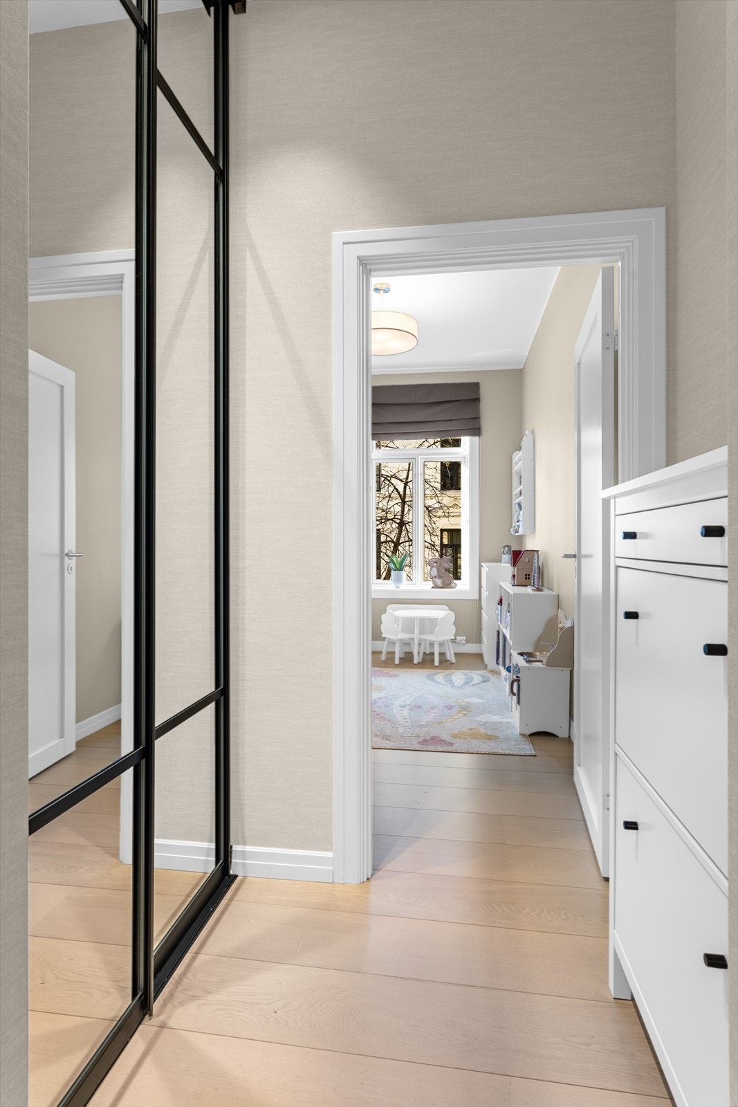 Mellomgang ved entréen med romslig og plassbygget skyvedørsgarderobe med speilfronter fra Skapnett (montert i 2023). Garderoben er hele 90 cm dyp og har praktisk innredning med hyller, skuffer samt både kort og langt heng. Skoskap medfølger. Galleribilde